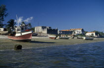 Fishing boats pulled up on shore with crenellated walls of fort behind Igbo African Eastern Africa Ibo Mozambiquean