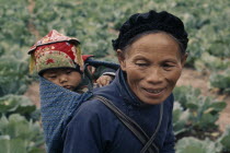 Woman from Miao minority people carrying child on her back in papoose.