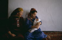 Women in traditional dress with baby at home.