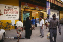 Street scene with people outside superstore with brightly coloured facade and advertising.  Colored