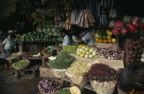 Vendors and open fronted stall with display of flowers  vegetables and spices.