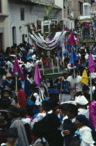 Easter procession through narrow street lined with spectators.