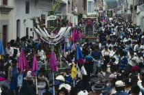 Easter procession through narrow street lined with spectators.