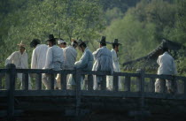 Confucian believers in traditional white robes and kat horsehair hats.