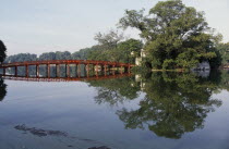 The Huc or Rising Sun bridge and trees reflected in Hoan Kiem Lake.