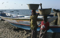 Girls carrying buckets of fish on their heads