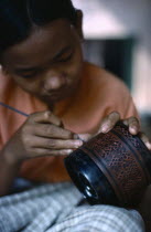 Woman applying lacquer to wood in factory workshop.Burma Pagan