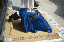 Buddhist wedding.  Bridegroom bows in religious submission.