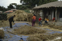 Farming family working outside thatched building