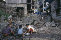 Women and children washing at piped water source in village.