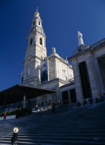 Woman wearing hat seated by steps beneath the church