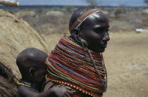 Samburu woman wearing traditional multi-strand necklaces with child on her back.