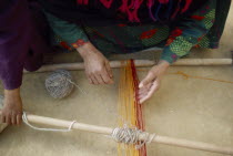 Cropped view of Bedouin woman and child weaving coloured yarn. Colored