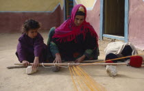 Bedouin woman and child in colourful dress weaving coloured yarn.Colored Colorful