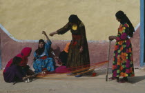 Group of Bedouin women in colourful dress weaving and spinning coloured yarn.Colored Colorful