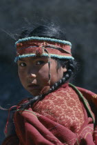 Portrait of young girl with hair in plaits and wearing woven head band decorated with turquoise beads.