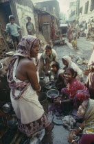 Women and children washing at standpipe in street in city slum area. Kolkata