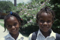 Head and shoulders portrait of two smiling schoolgirls with braided hair. Greneda