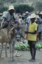 Market scene with two young boys with donkey carrying basket panniers.