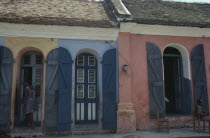 Street scene with typical colonial style architecture and young woman standing in doorway.