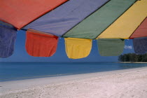 Close up of a multi coloured parasol on the sandy beach.   Colored umbrella