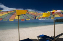 Two multi coloured parasols and  sun loungers on the sandy beach  boat in the distance.Colored umbrella