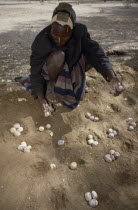 Turkana man playing traditional mathematical game of Ajua.