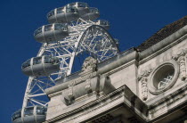 The British Airways London Eye or Millennium Wheel.  Part view seen behind corner of exterior wall of the London Aquarium.