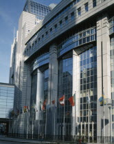 The European Parliament Building  modern exterior with line of flagpoles flying European flags.