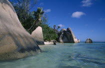 Rock formations along the coast with a woman bather walking into the turquoise sea