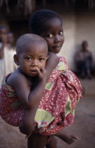 Young girl looking after little sister carried on her back.