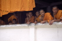 Young monks leaning over monastery wall.