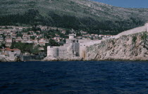 View across water towards the Old City fortifications along the coastline and houses built into the hillside.