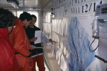 Station of Italian Antarctica Progamme. Interior with people pointing towards a map on the wall