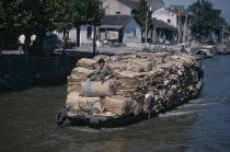 Man on boat travelling along the Grand Canal carrying piles of cardboard between Suzhou to wuxi