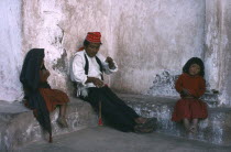 Taquile man spinning wool with his two children sitting either side of him.