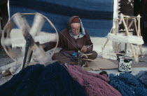 Elderly man spinning wool for rug making.