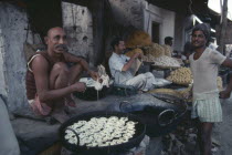 Man cooking fried snacks at pavement food stall.