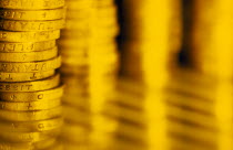 Close view of piled English pound coins and indistinct reflection.