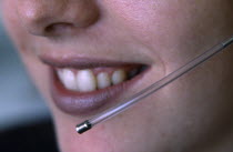 Female telesales operator wearing a telephone head set.  Close up of lower half of face and mouthpiece.