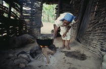 Woman cooking over open fire.