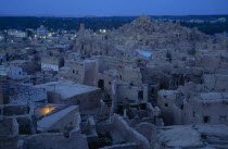 View across town towards Shali Fortress at night with oasis in the background