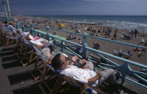 View over people in deckchairs lining the promenade toward the busy beach