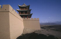 View along turreted wall toward traditional building above and landscape below