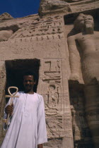 Man holding key of life in front of temple statue and hieroglyphics