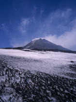 The summit cone seen from across a lava field covered with snow.      volcano