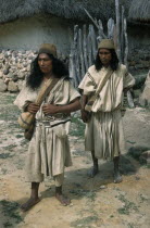 Nabusimaque village.  Two Ika men in traditional woven mantas / cloaks  with  fique  / cactus fibre helmets and woven wool  mochilas  / shoulder bags with Ika designsIndigenous Tribes Caribbean coast...