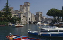 Sirmione castle with boats moored on the lake in the foreground.