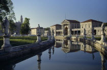 Prato della Valle.  Canal surrounding oval green island along which stand statues of famous cultural figures.