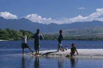 Group of children with a small dog fishing in the bay and mountains seen across water